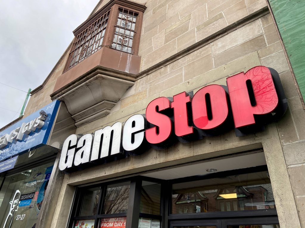 GameStop storefront with 3D logo on stone building and General Vision Services shop Queens NYC Wallpaper
