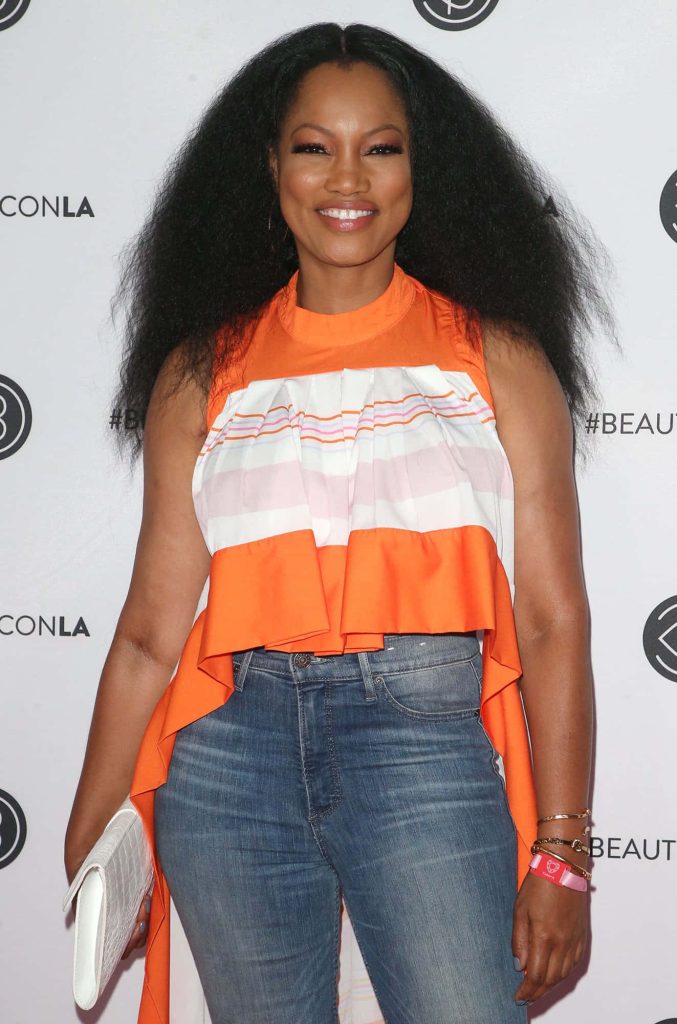 Garcelle Beauvais smiling in chic orange white ruffled top and jeans at Beautycon event Wallpaper