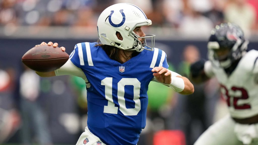 Gardner Minshew II in blue Colts jersey throwing football mid-game vibrant NFL wallpaper background