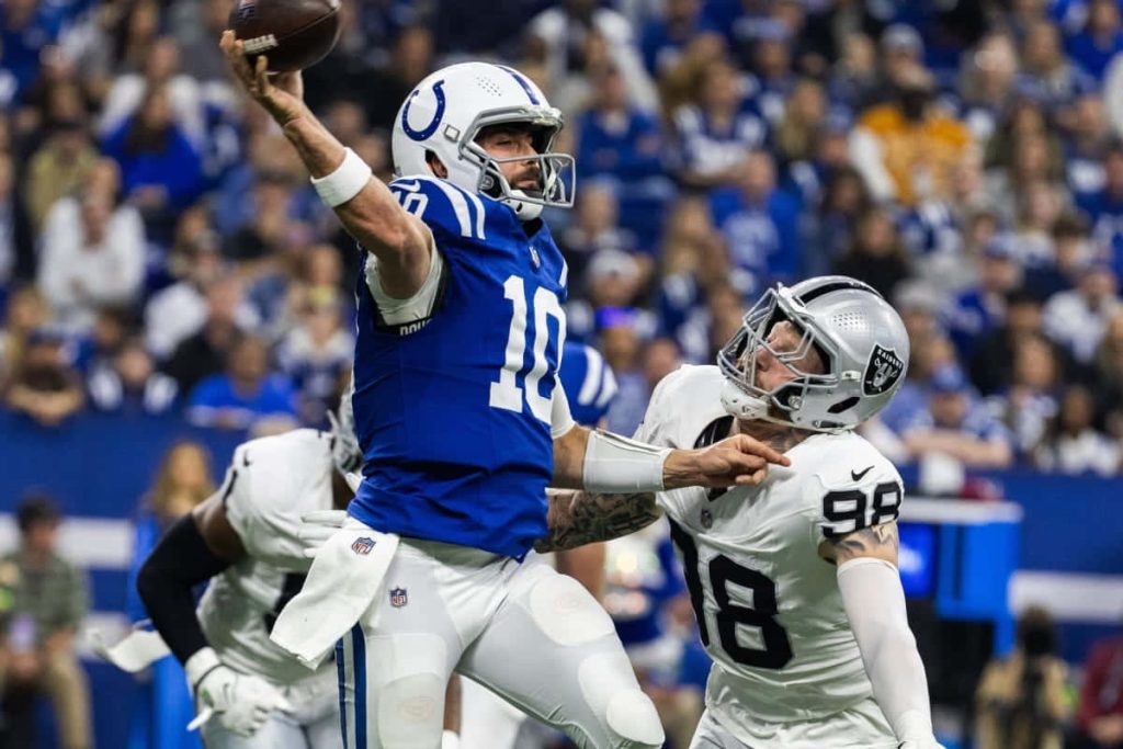 Gardner Minshew II throws under pressure from Raiders defender in vibrant NFL action wallpaper
