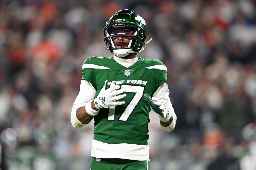 Garrett Wilson in green Jets jersey 17 ready on field with stadium lights and blurred crowd Wallpaper