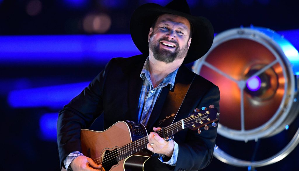 Garth Brooks live concert playing Takamine guitar cowboy hat blue stage lighting spotlight Wallpaper