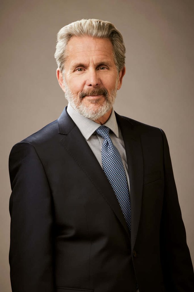 Gary Cole studio portrait in dark suit and blue tie with soft lighting on neutral background wallpaper