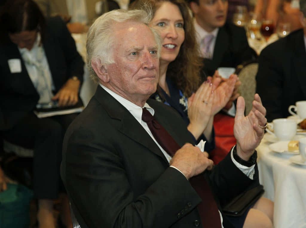 Gary Hart clapping in dark suit at professional banquet event high-quality wallpaper background