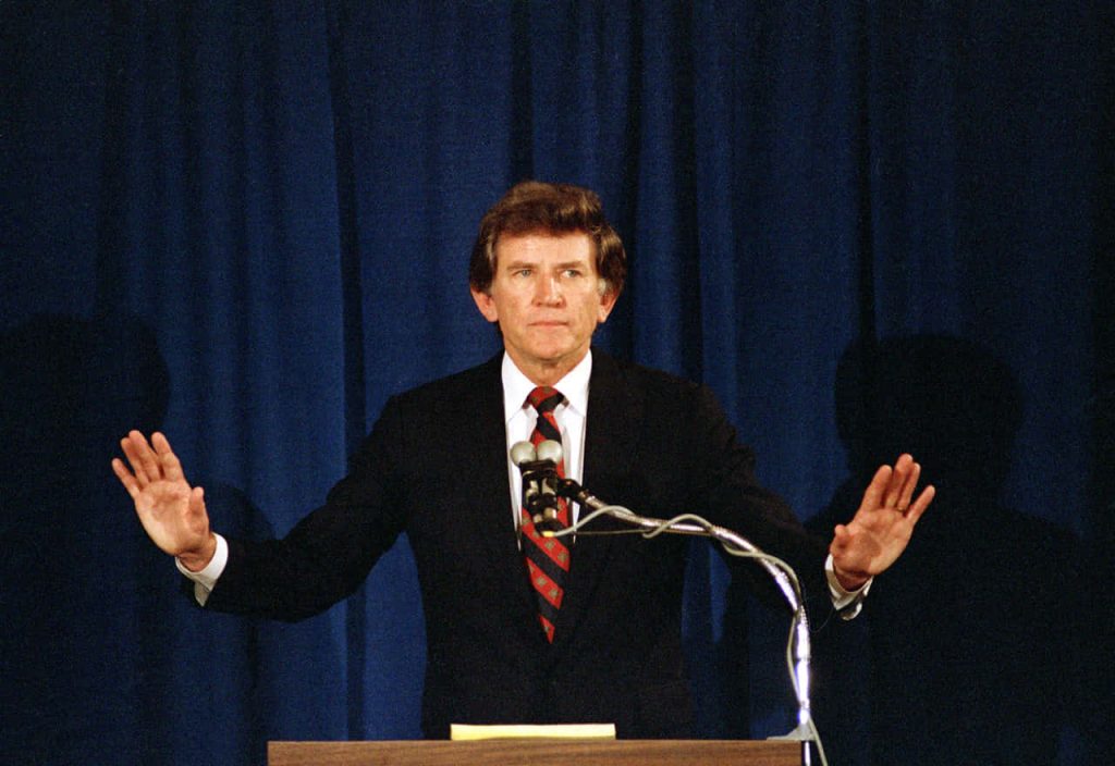Gary Hart former senator speaking behind podium blue curtain classic political moment wallpaper