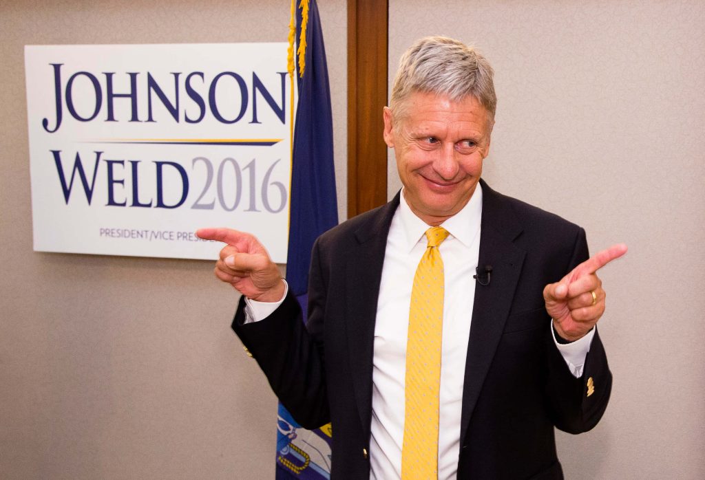 Gary Johnson in sharp suit and yellow tie points both ways at Johnson Weld 2016 backdrop Wallpaper