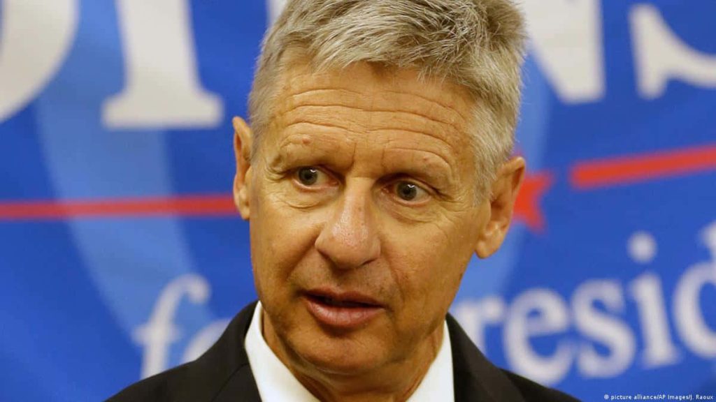 Portrait of Gary Johnson speaking at campaign event with blue backdrop and focused expression Wallpaper