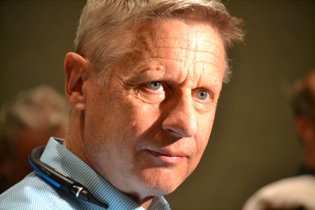 Candid close-up of Gary Johnson in light blue shirt deep in thought with warm indoor lighting Wallpaper