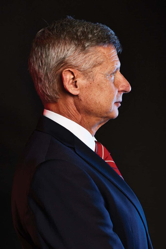 Gary Johnson side profile portrait in suit and red tie on dark moody background wallpaper