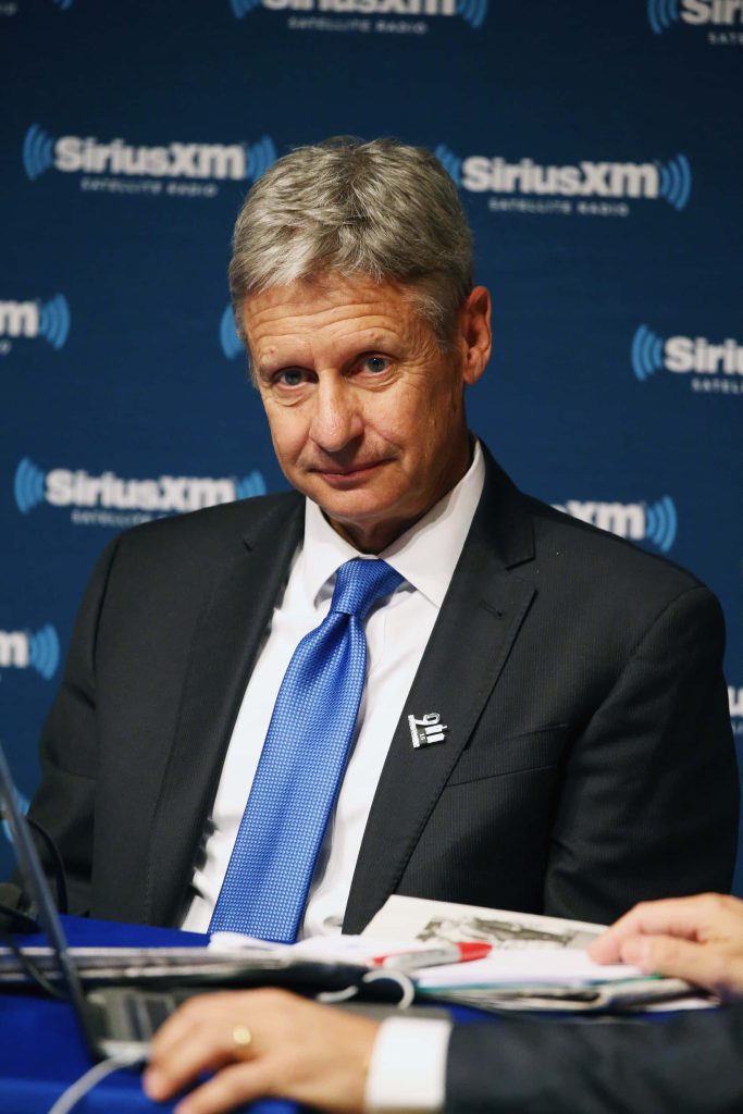 Gary Johnson professional portrait in dark suit blue tie 911 lapel pin SiriusXM studio background Wallpaper
