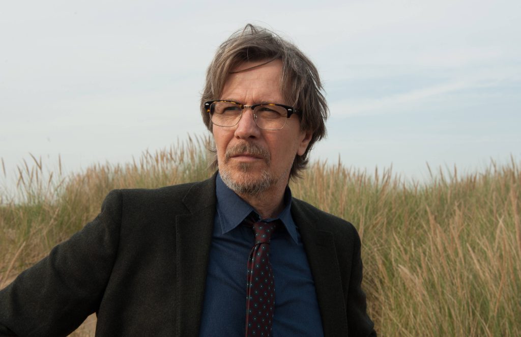Gary Oldman as Quaker Wells in blazer by dune grass cinematic Paranoia movie wallpaper background