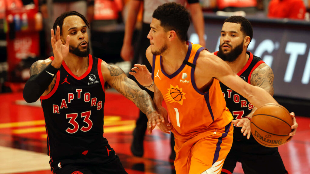 Gary Trent Jr defends Devin Booker in Phoenix Suns orange uniform during intense NBA game action Wallpaper