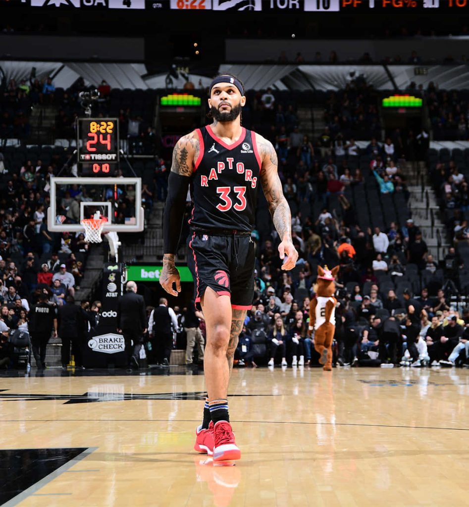 Gary Trent Jr in Toronto Raptors jersey #33 on court vs San Antonio Spurs with mascot background Wallpaper