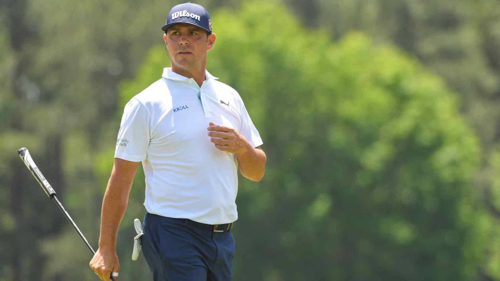 Professional golfer Gary Woodland in white polo and Wilson cap walking golf course with putter Wallpaper