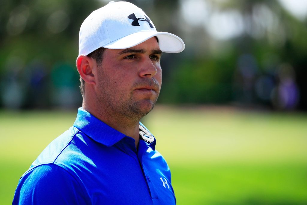 Professional golfer Gary Woodland in blue polo and white cap on lush golf course background Wallpaper