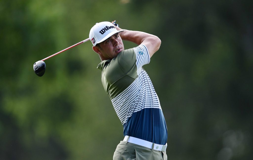 Professional golfer Gary Woodland mid-swing on green golf course wearing Wilson cap and polo Wallpaper