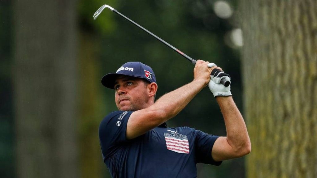 Professional golfer Gary Woodland in dark blue polo swings on green golf course background Wallpaper