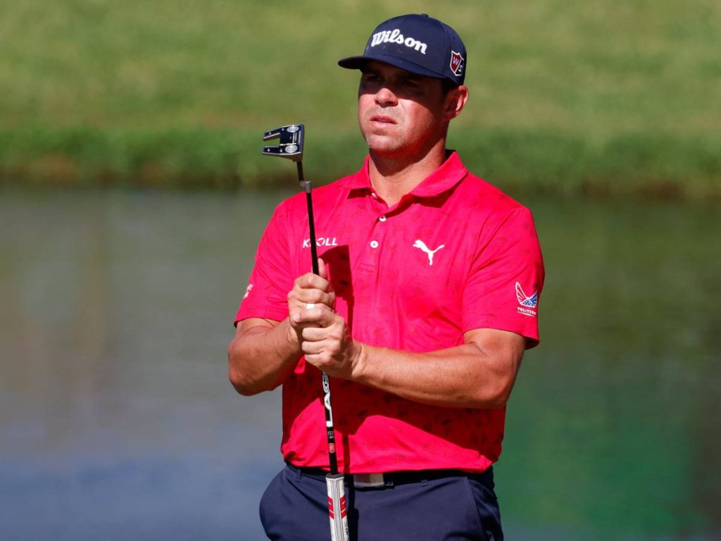Gary Woodland focused on green gripping putter wearing red Puma polo and Wilson cap outdoors Wallpaper