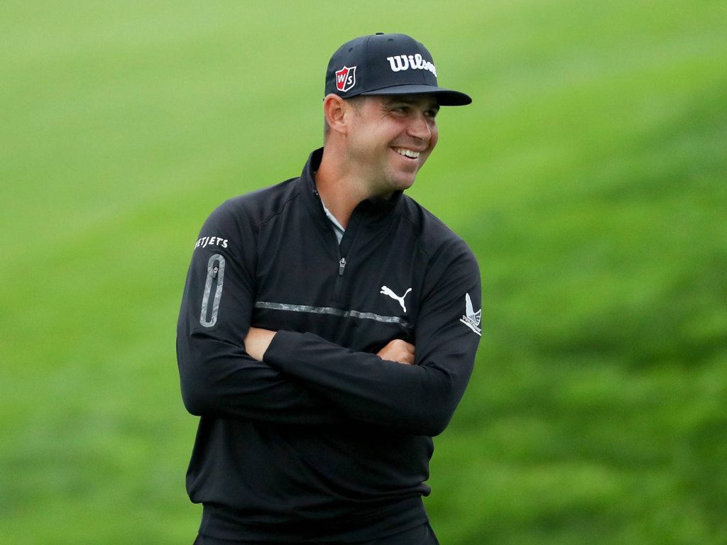 Professional golfer Gary Woodland smiling in black Puma pullover on vibrant green golf course background Wallpaper