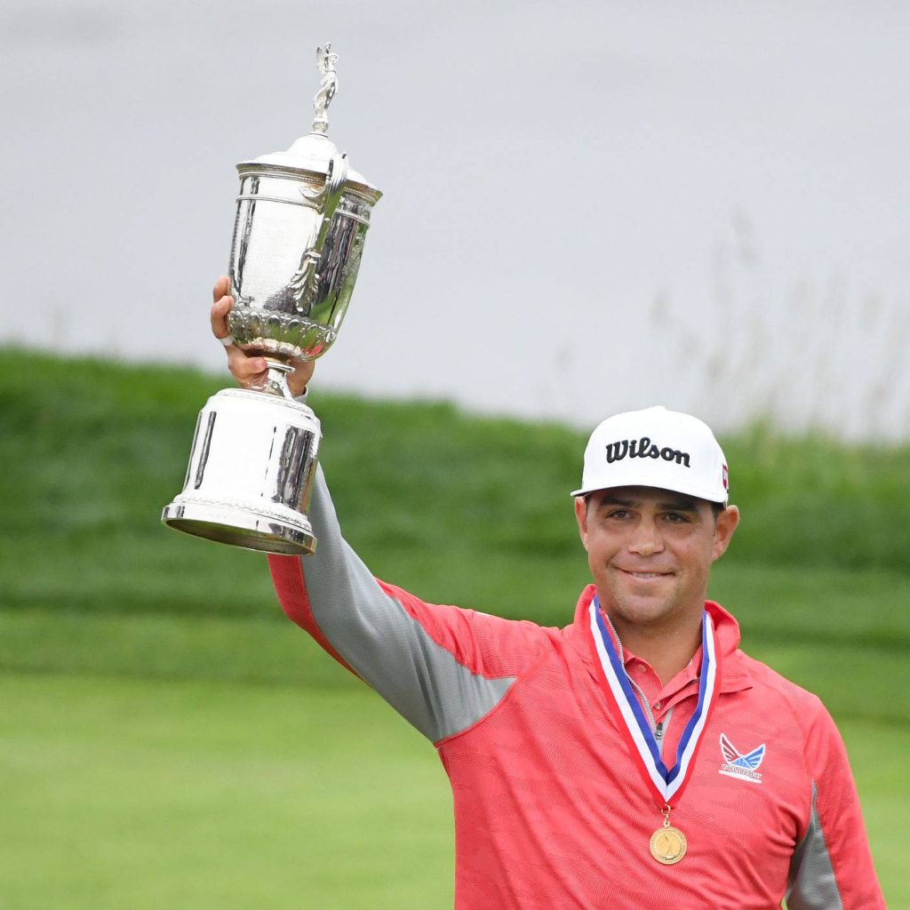 Gary Woodland celebrating U.S. Open victory trophy on golf course in red shirt and white cap Wallpaper