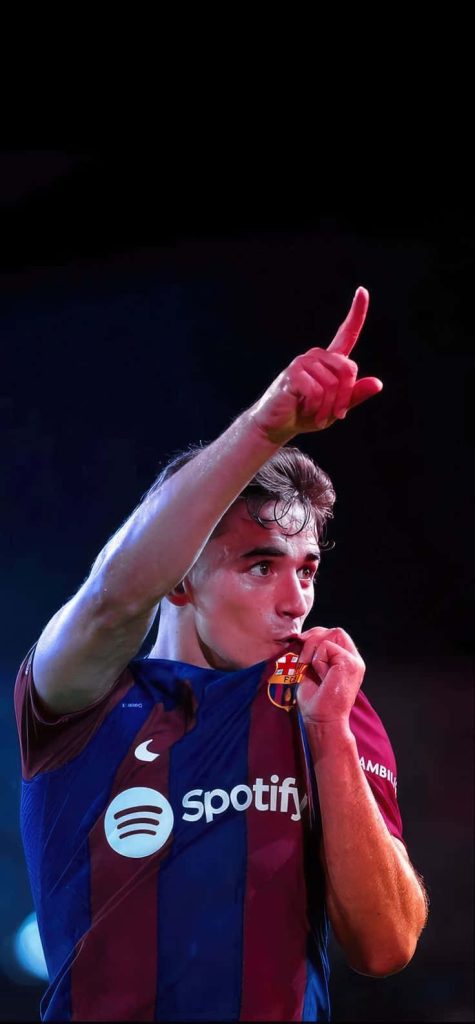 Gavi FC Barcelona midfielder kissing club crest in dramatic lighting dark background wallpaper
