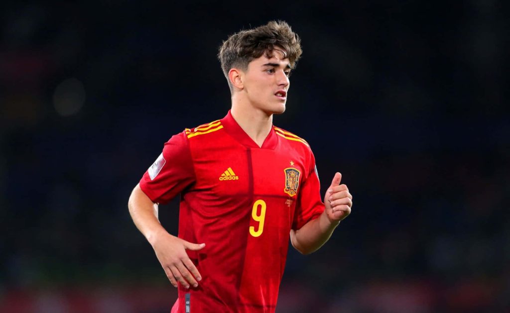 Spain football star Gavi in red kit number 9 action shot with focused expression stadium background wallpaper
