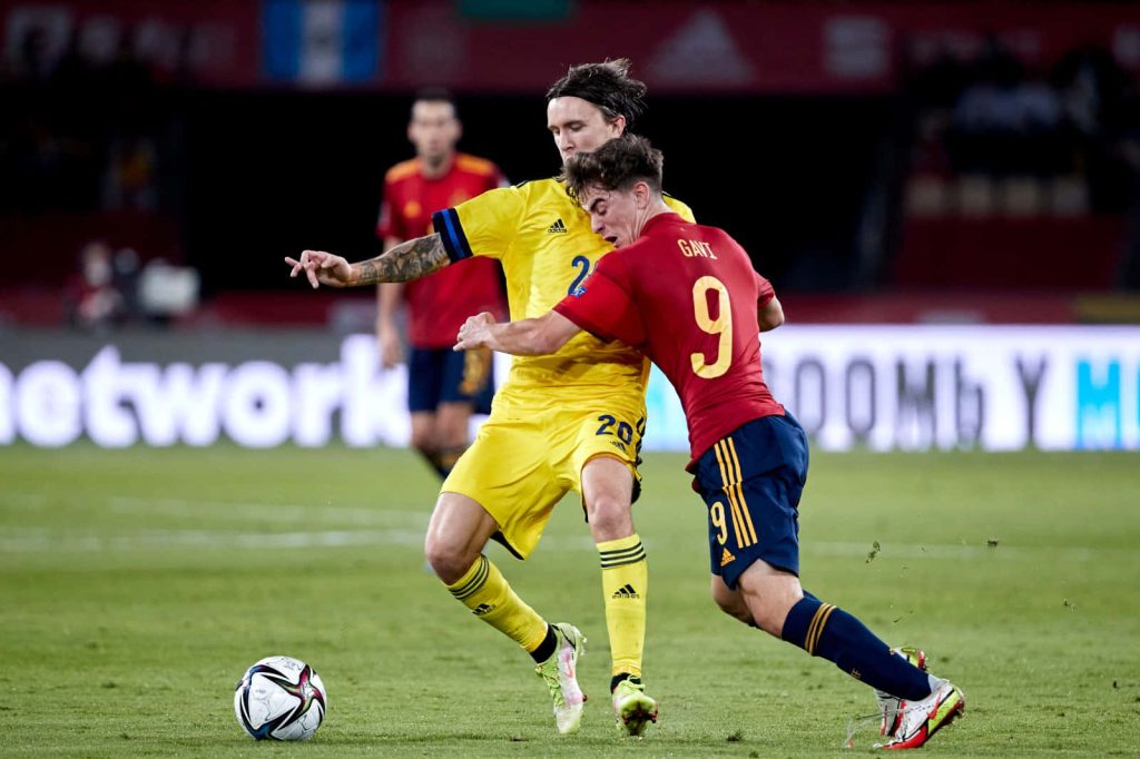 Gavi Spain football action intense midfield battle red jersey dynamic sports wallpaper background