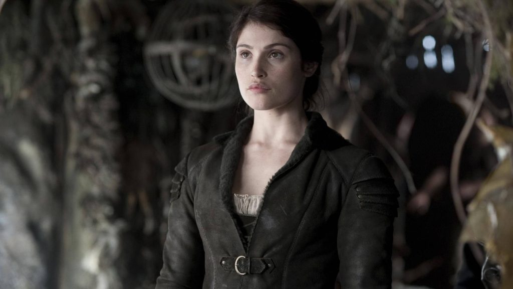 Gemma Arterton intense portrait in rugged leather jacket with fur against rustic dim background Wallpaper