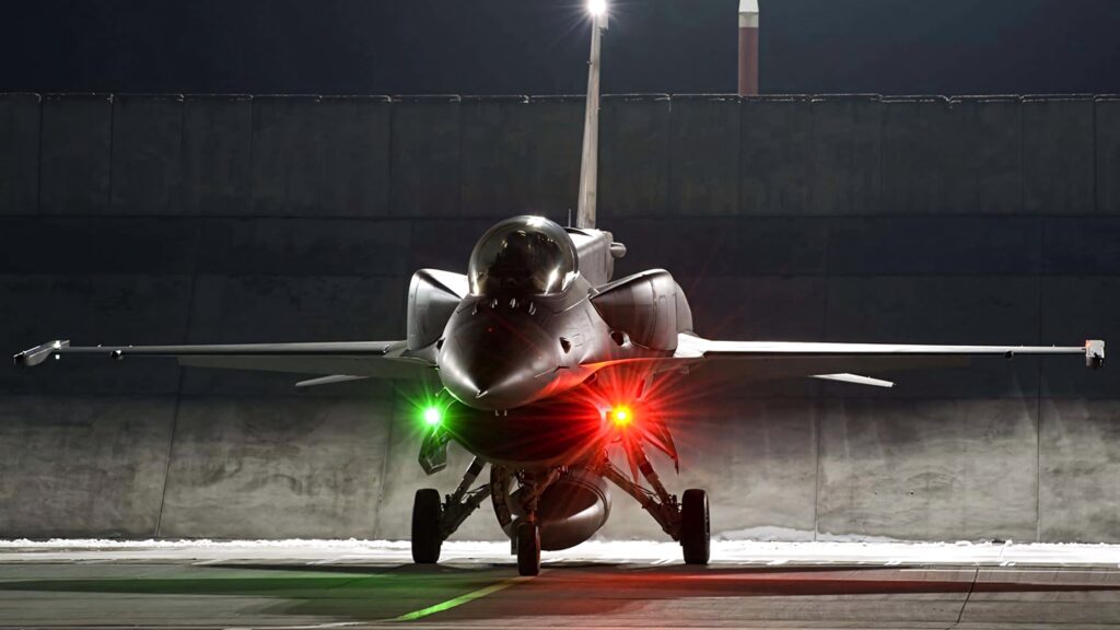 General Dynamics F-16 Fighting Falcon on runway at night with red and green navigation lights Wallpaper