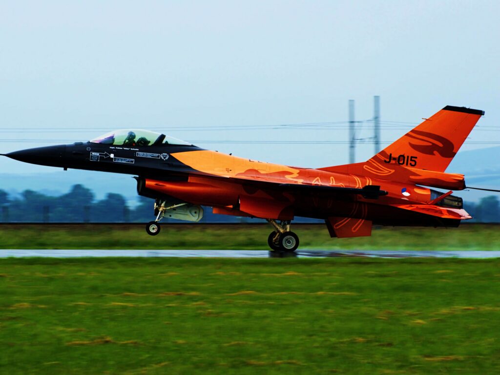 General Dynamics F-16 Fighting Falcon orange black livery speed runway overcast sky wallpaper