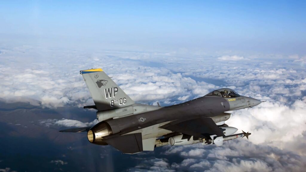 General Dynamics F-16 Fighting Falcon jet soaring above clouds with gray camouflage and tail markings Wallpaper