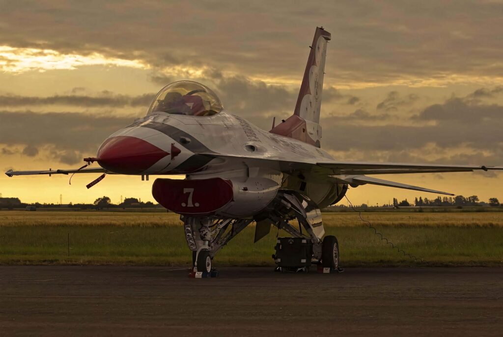 General Dynamics F-16 Fighting Falcon on tarmac at sunset with polished silver red livery Wallpaper