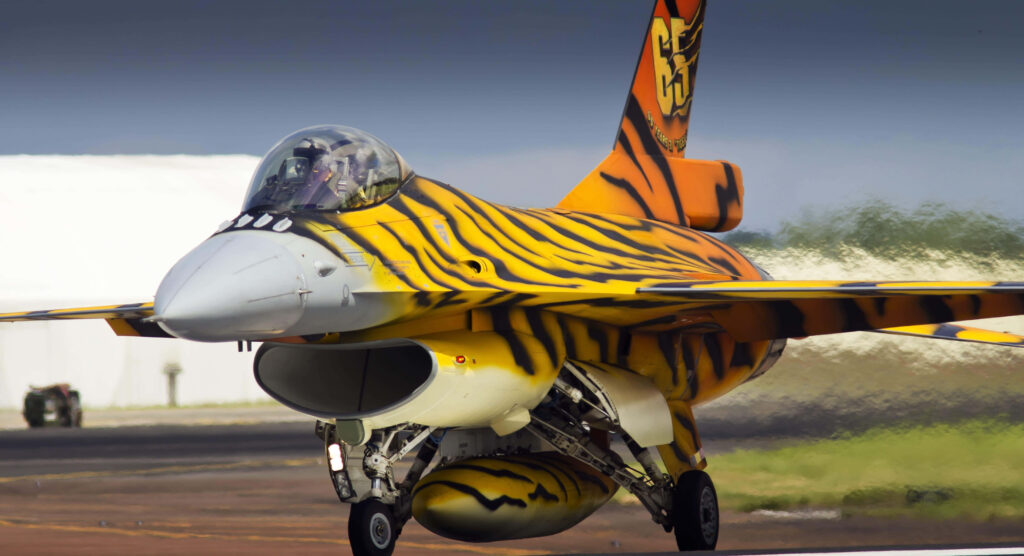 General Dynamics F-16 Fighting Falcon with vivid orange tiger stripe livery on runway motion blur Wallpaper