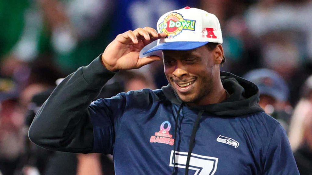 Seattle Seahawks quarterback Geno Smith smiling in Pro Bowl cap and navy hoodie wallpaper
