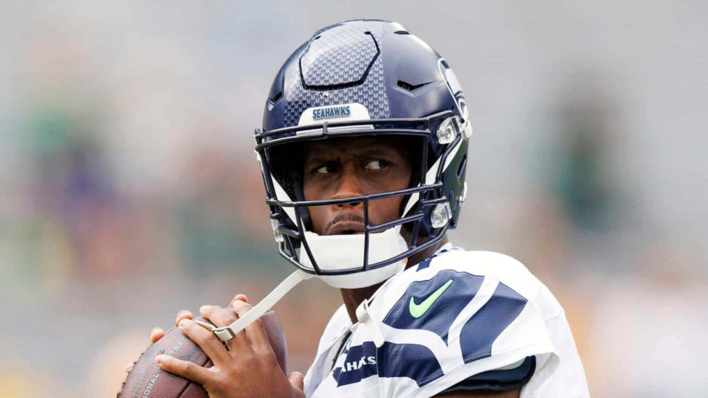Seattle Seahawks quarterback Geno Smith focused holding football in helmet and white jersey wallpaper