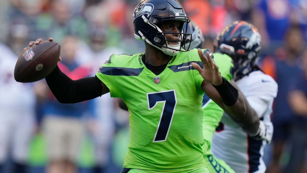 Seattle Seahawks quarterback Geno Smith in neon green jersey throwing ball intense NFL action shot Wallpaper