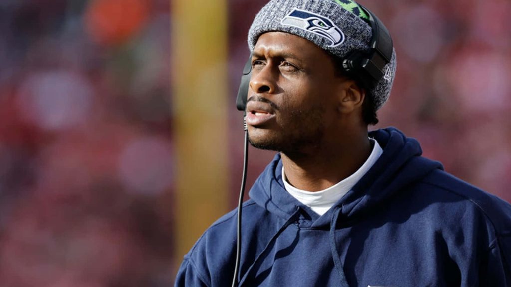 Seattle Seahawks quarterback Geno Smith focused in team beanie headset navy hoodie game day portrait Wallpaper