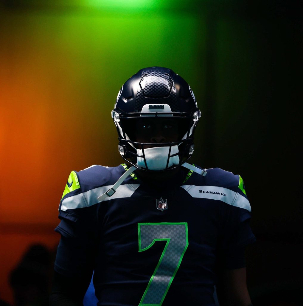 Seattle Seahawks quarterback Geno Smith in navy jersey 7 with vibrant green orange lighting background Wallpaper