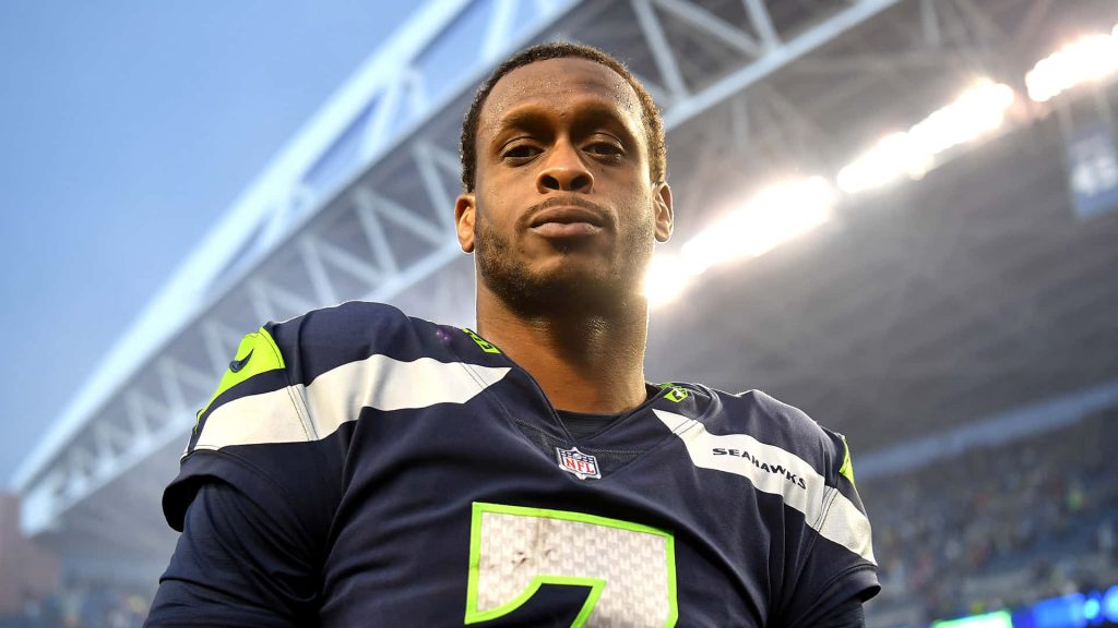 Seattle Seahawks quarterback Geno Smith in navy neon green jersey under stadium lights Wallpaper