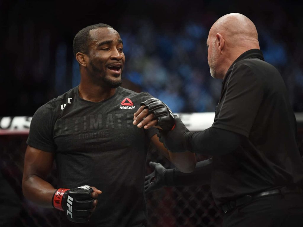 UFC fighter Geoff Neal in black Reebok gear with referee in dramatic octagon fight scene wallpaper