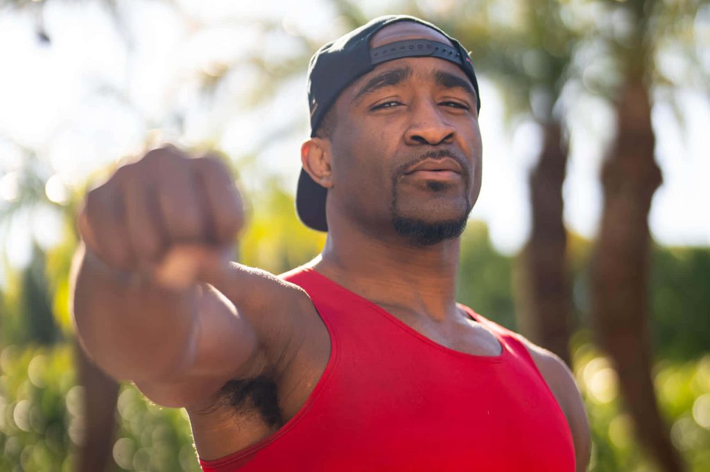 UFC fighter Geoff Neal in red tank top and cap punches forward outdoors high-quality wallpaper