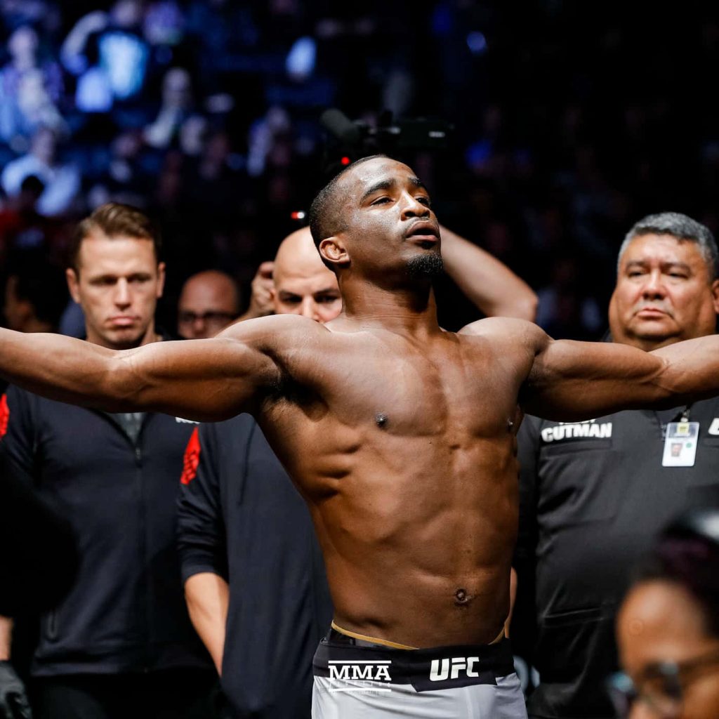 UFC fighter Geoff Neal shirtless with arms outstretched during intense official weigh-in lighting Wallpaper