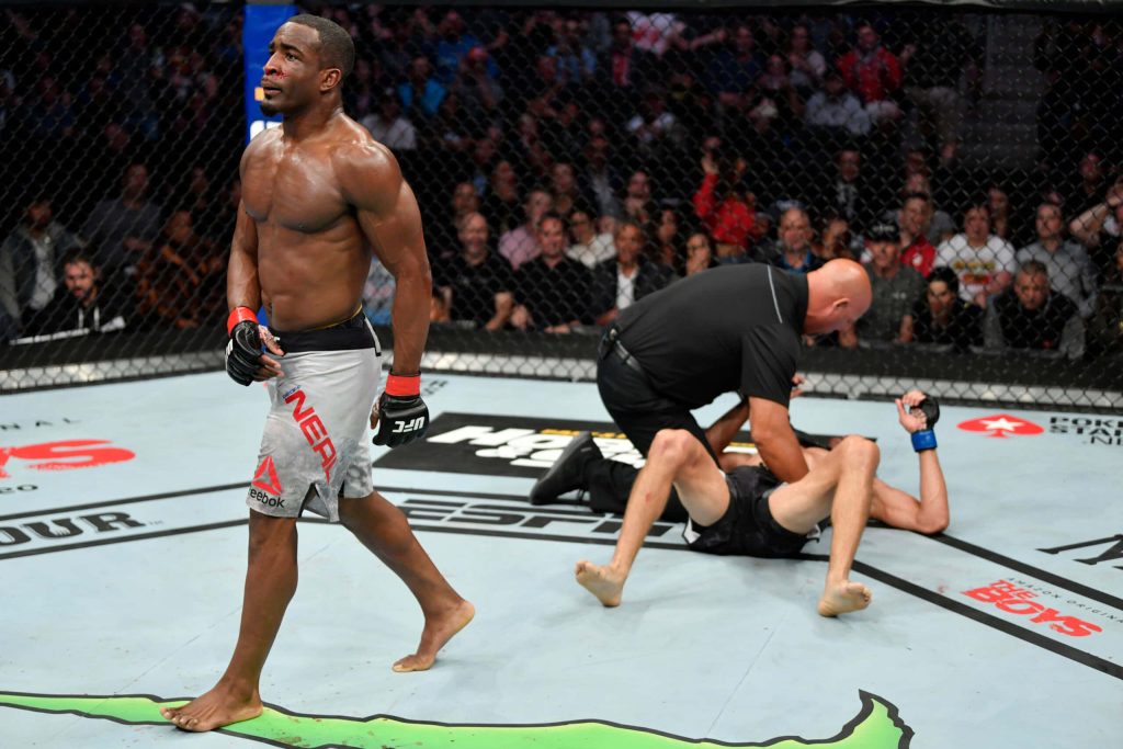 Geoff Neal walking away after UFC fight with referee attending opponent in Octagon arena Wallpaper