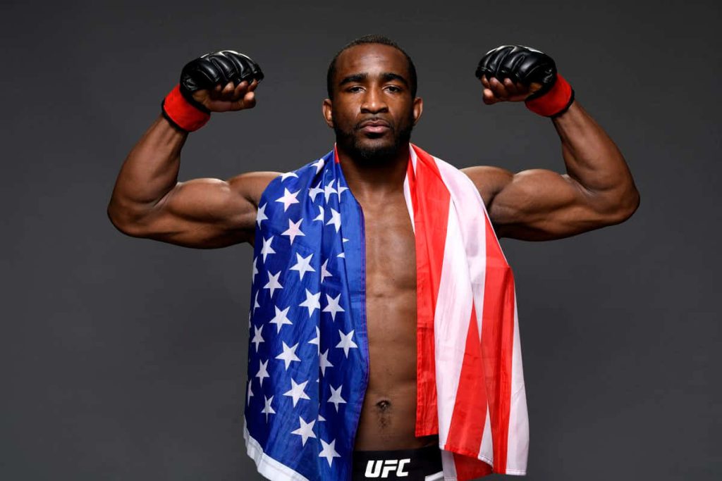 UFC fighter Geoff Neal posing confidently with American flag and black gloves on grey background Wallpaper