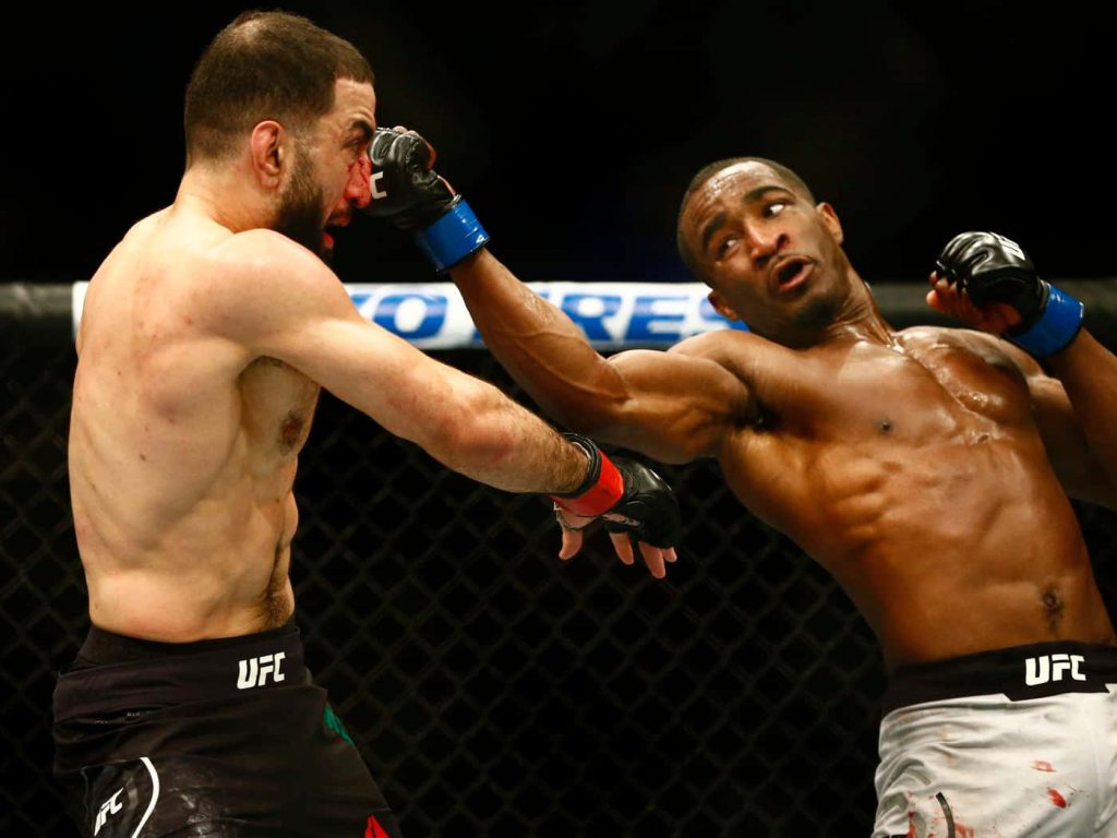 UFC fighters Geoff Neal and Belal Muhammad in intense Octagon fight landing powerful punch Wallpaper