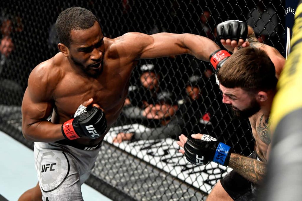Geoff Neal landing a powerful strike on Mike Perry inside UFC Octagon with stadium lights Wallpaper