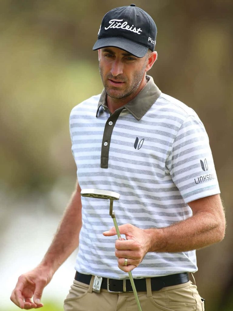 Professional golfer Geoff Ogilvy focused holding putter in striped polo and Titleist cap outdoors Wallpaper