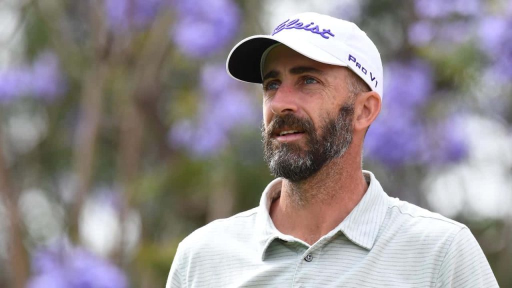 Professional portrait of golfer Geoff Ogilvy with beard and Titleist cap vibrant purple flowers background Wallpaper