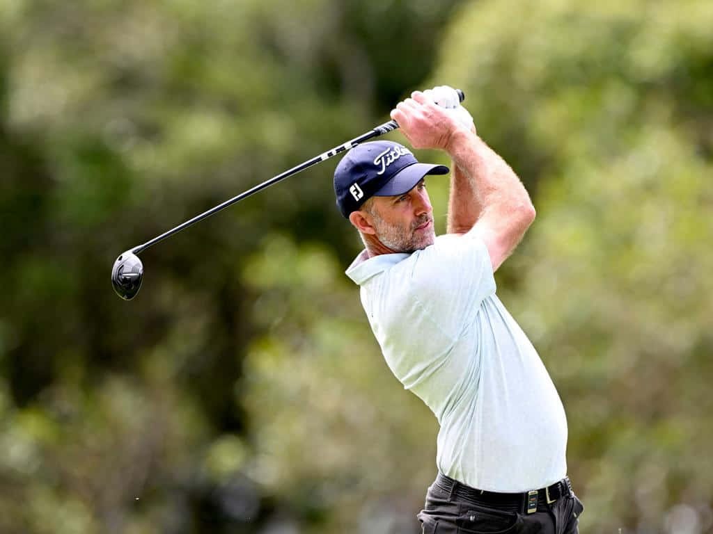 Professional golfer Geoff Ogilvy mid golf swing follow-through wearing Titleist cap on green course Wallpaper