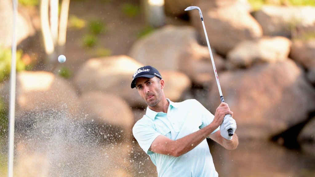 Professional golfer Geoff Ogilvy hitting a splash shot in light blue polo on rocky golf course Wallpaper